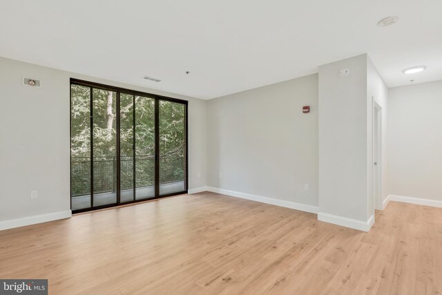 unfurnished room featuring light hardwood / wood-style floors, floor to ceiling windows, and plenty of natural light