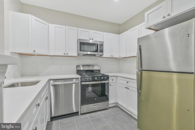 kitchen with white cabinetry, stainless steel appliances, backsplash, and light tile patterned floors