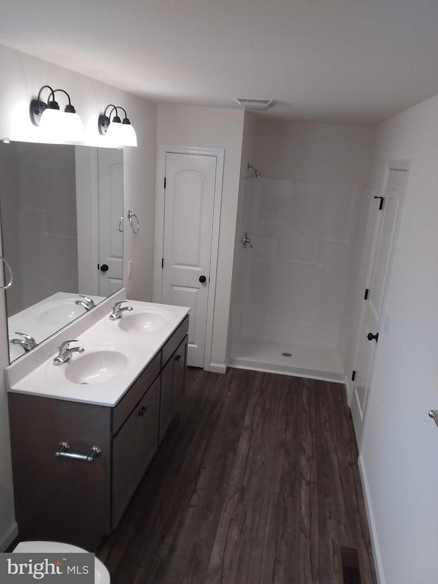 bathroom with walk in shower, hardwood / wood-style flooring, and vanity