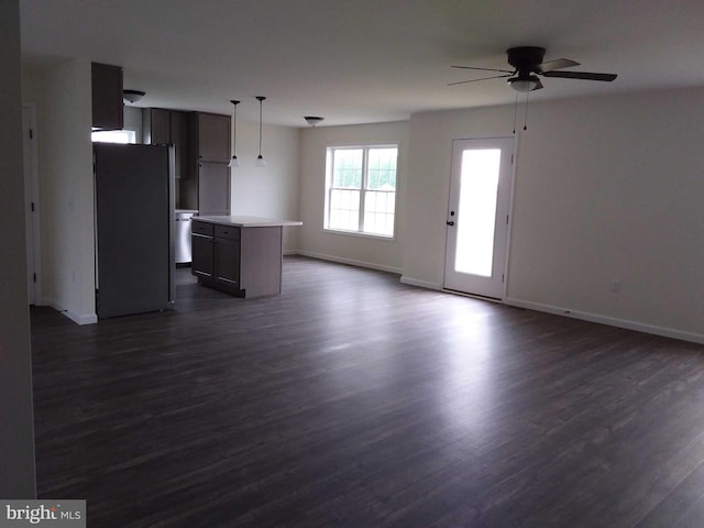 unfurnished living room featuring dark wood-type flooring and ceiling fan