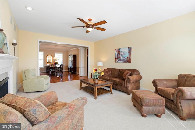 living room with ornate columns, wood-type flooring, and ceiling fan with notable chandelier