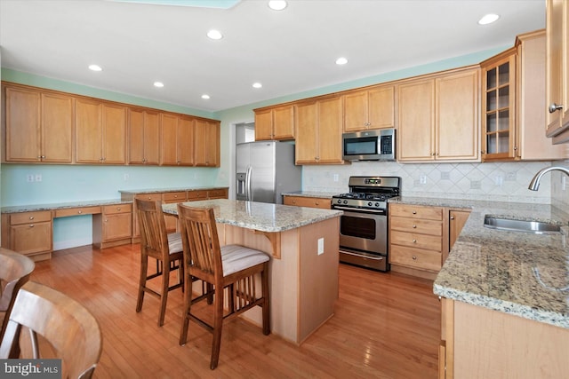 kitchen featuring appliances with stainless steel finishes, a kitchen island, sink, and light hardwood / wood-style flooring