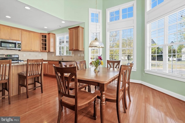 dining space featuring sink, a towering ceiling, and light hardwood / wood-style floors