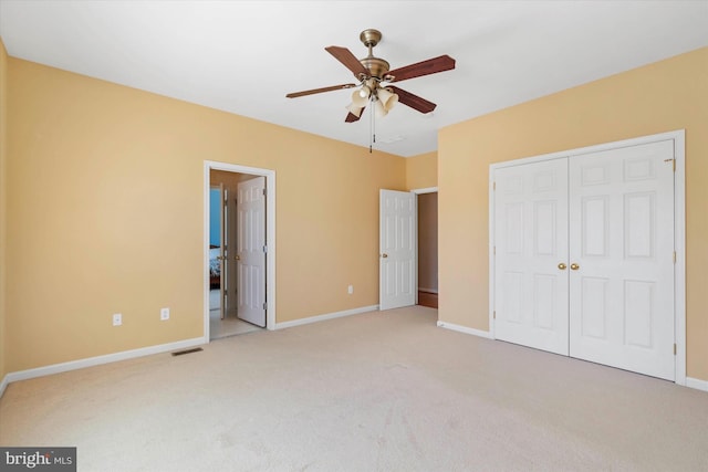 unfurnished bedroom with ceiling fan, light colored carpet, and a closet