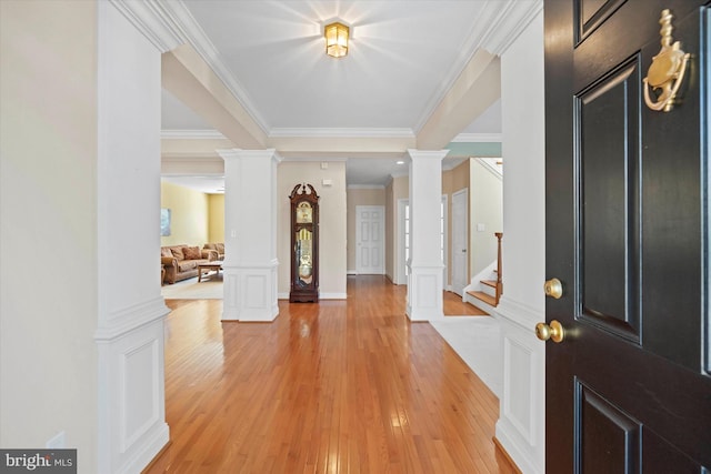 entryway featuring ornate columns, ornamental molding, and light hardwood / wood-style flooring