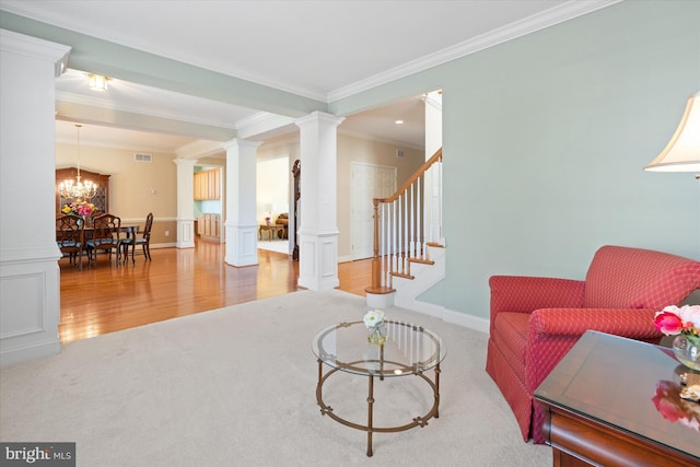 living room with ornate columns, hardwood / wood-style floors, ornamental molding, and a chandelier