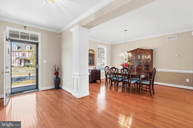 dining area featuring ornamental molding, decorative columns, an inviting chandelier, and light hardwood / wood-style flooring