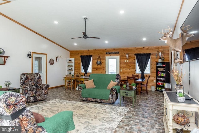 living room featuring ornamental molding, vaulted ceiling, wooden walls, and ceiling fan