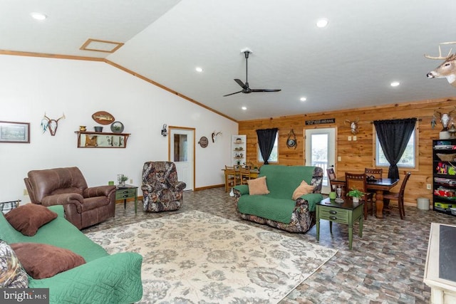 living room featuring crown molding, ceiling fan, wood walls, and vaulted ceiling