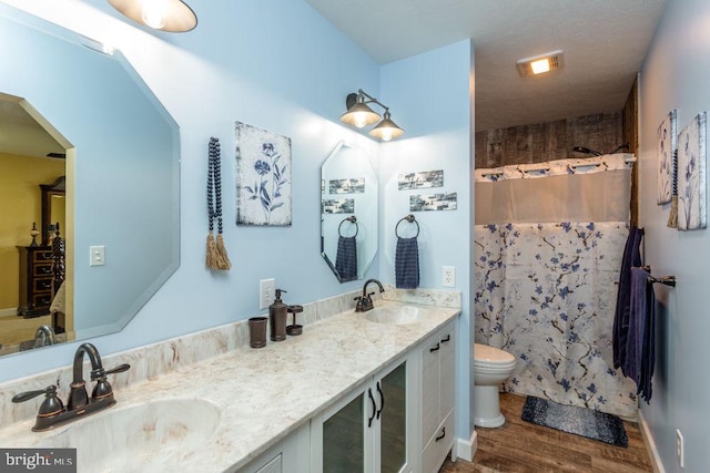 bathroom with hardwood / wood-style flooring, vanity, toilet, and curtained shower