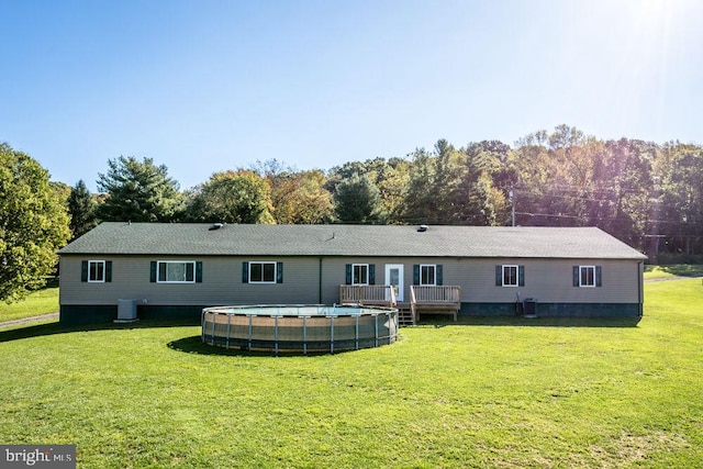 rear view of property with central AC, a yard, and a swimming pool side deck