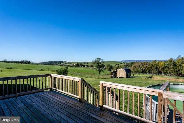 wooden deck featuring a rural view, a storage shed, and a lawn