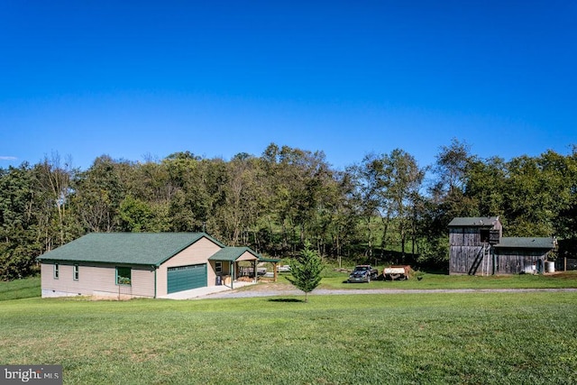 view of yard featuring a garage, a carport, and an outbuilding