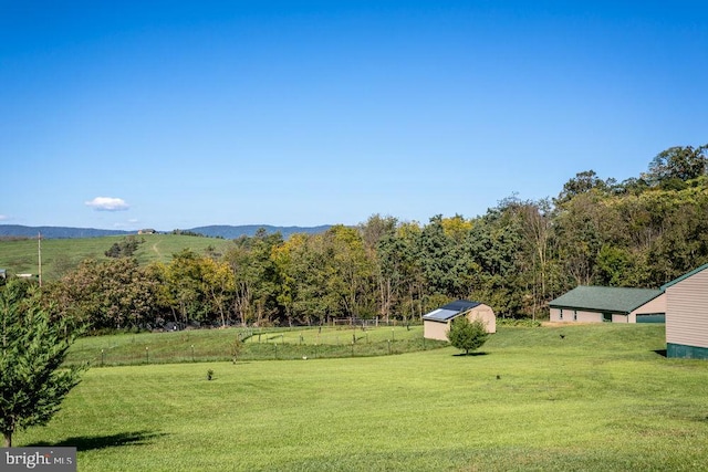 view of yard featuring a mountain view, a storage shed, and a rural view