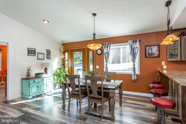 dining area featuring lofted ceiling and dark hardwood / wood-style floors