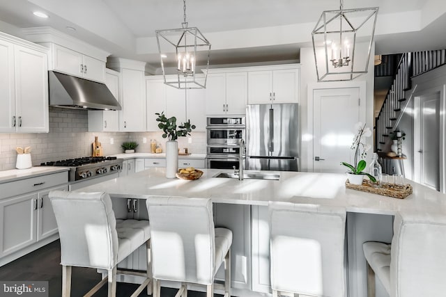 kitchen featuring hanging light fixtures, appliances with stainless steel finishes, a kitchen bar, and white cabinetry