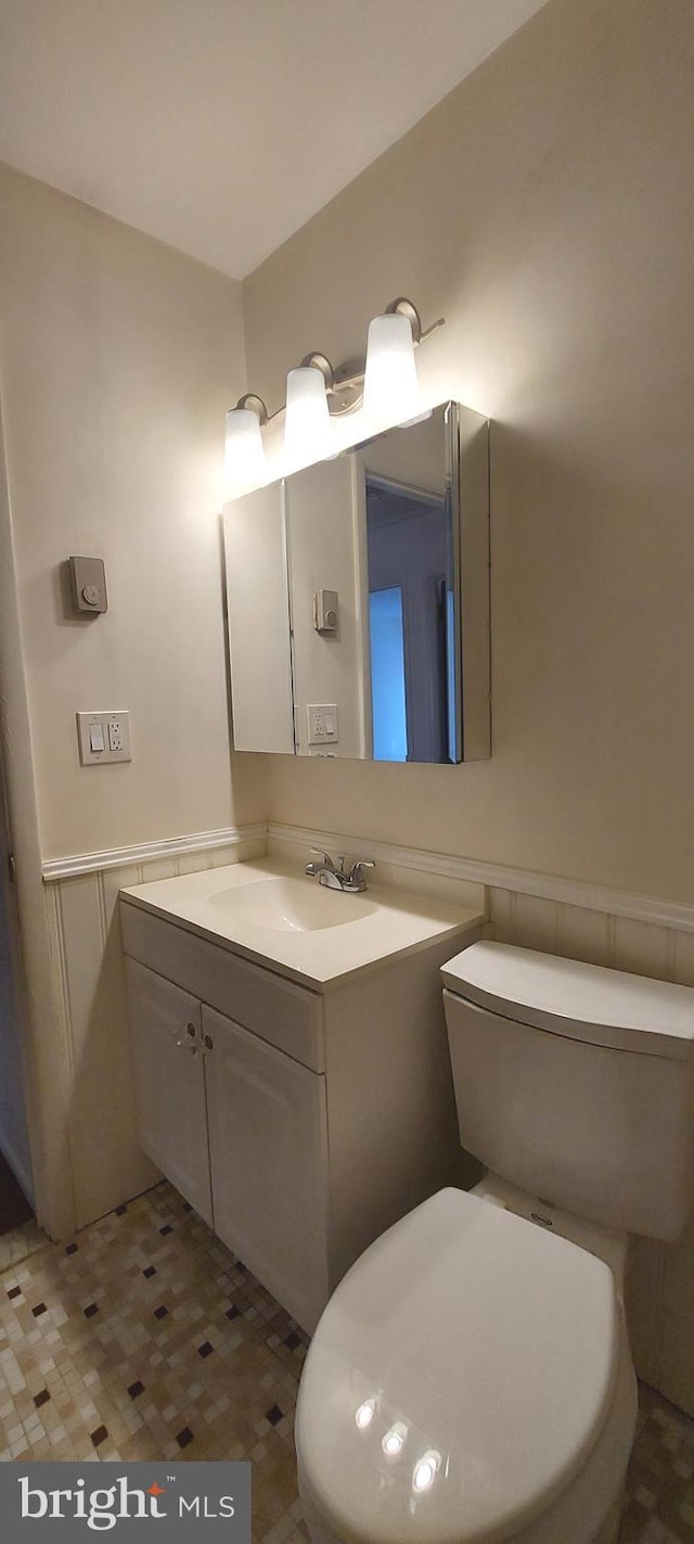 bathroom with toilet, wainscoting, and vanity