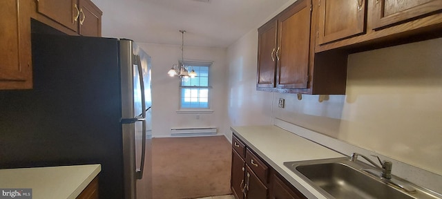 kitchen featuring a sink, baseboard heating, freestanding refrigerator, and light countertops