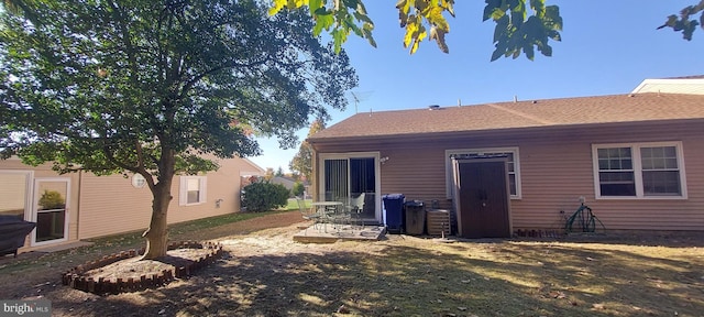 rear view of property featuring central AC and a lawn