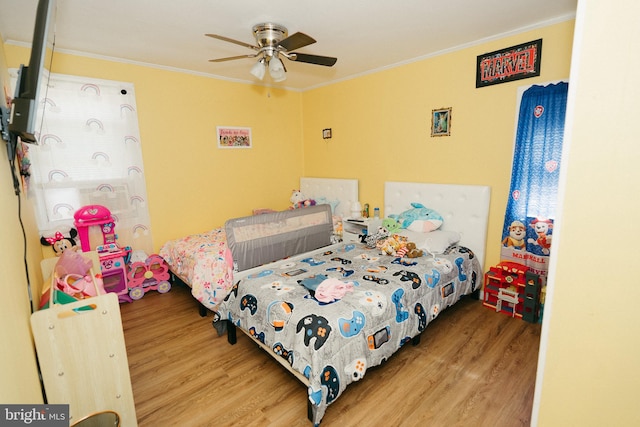 bedroom featuring wood-type flooring, ornamental molding, and ceiling fan