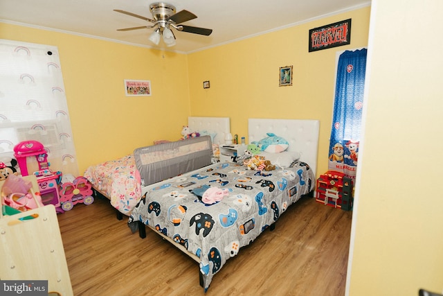 bedroom with crown molding, hardwood / wood-style flooring, and ceiling fan