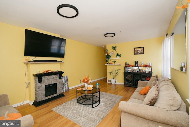 living room with hardwood / wood-style flooring and a stone fireplace