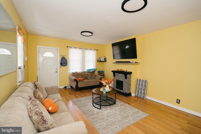 living room featuring wood-type flooring and a stone fireplace