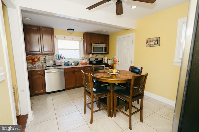 kitchen featuring light tile patterned flooring, backsplash, appliances with stainless steel finishes, and ceiling fan