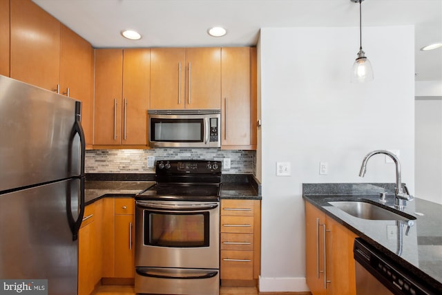 kitchen featuring appliances with stainless steel finishes, decorative light fixtures, and dark stone counters