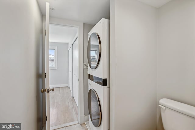 washroom with light hardwood / wood-style flooring and stacked washer and clothes dryer