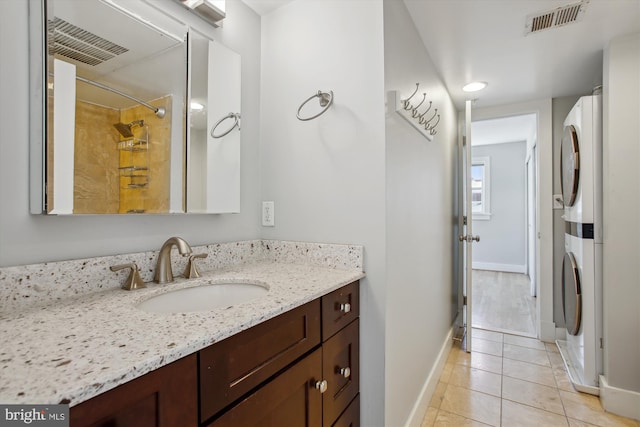 bathroom featuring vanity, stacked washer and dryer, a shower with curtain, and tile patterned flooring