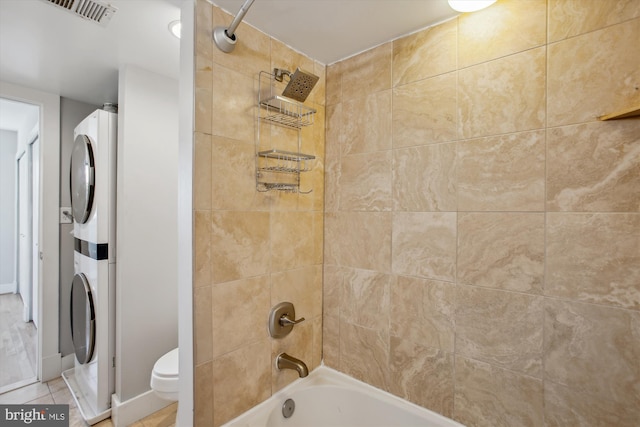 bathroom with stacked washer / drying machine, shower / tub combo with curtain, tile patterned floors, and toilet