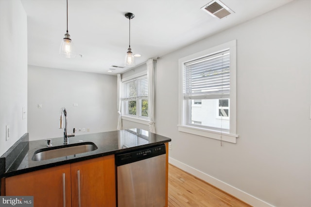 kitchen featuring dishwasher, dark stone counters, sink, pendant lighting, and light wood-type flooring