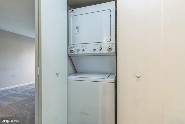 clothes washing area featuring stacked washer / drying machine and carpet flooring