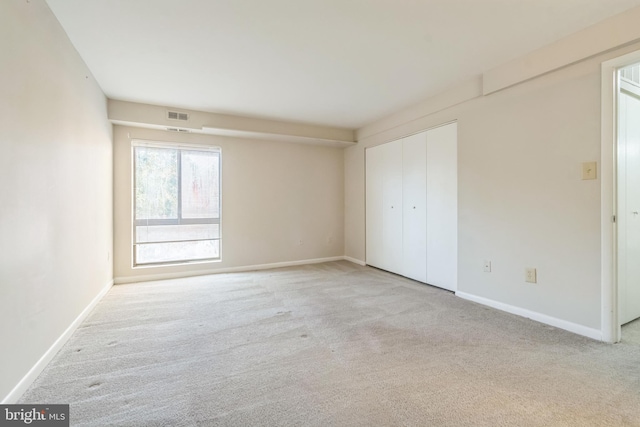 unfurnished bedroom featuring light carpet and a closet