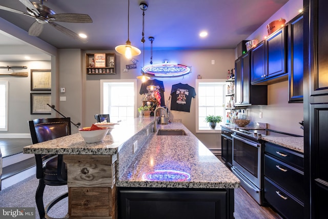 kitchen featuring a breakfast bar, stainless steel range with electric cooktop, sink, and an island with sink