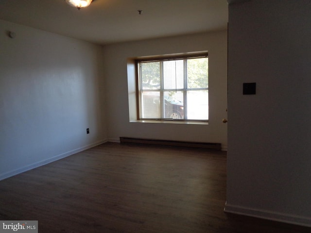 empty room featuring baseboard heating and dark hardwood / wood-style floors