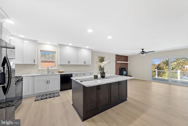 kitchen with black appliances, white cabinets, and a healthy amount of sunlight