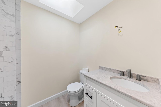 bathroom with vanity, hardwood / wood-style flooring, toilet, and a skylight