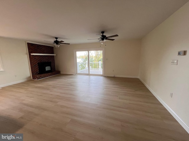 unfurnished living room with a brick fireplace, light wood-type flooring, and ceiling fan