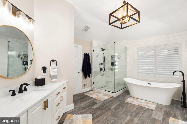 bathroom with a notable chandelier, vanity, and plus walk in shower