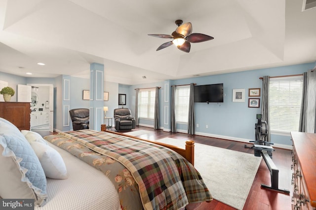 bedroom with hardwood / wood-style floors, a tray ceiling, and ceiling fan