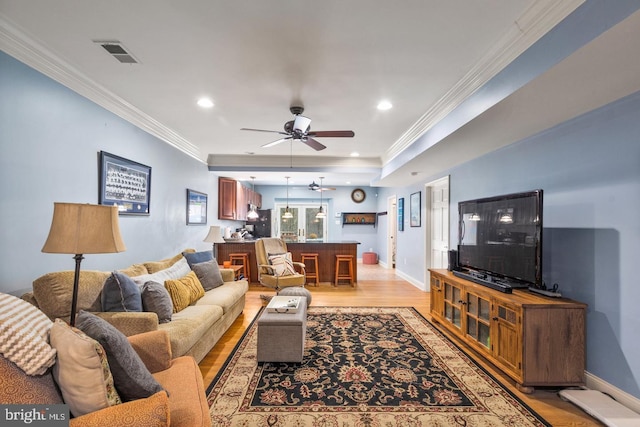 living room with light wood-type flooring, ceiling fan, and ornamental molding