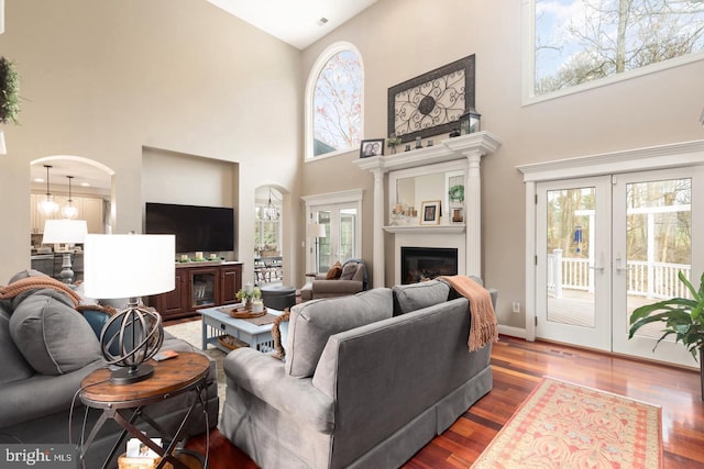 living room featuring wood-type flooring, french doors, and a high ceiling