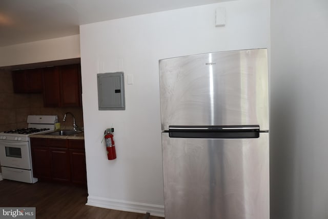 kitchen featuring stainless steel refrigerator, sink, dark wood-type flooring, white gas range oven, and electric panel