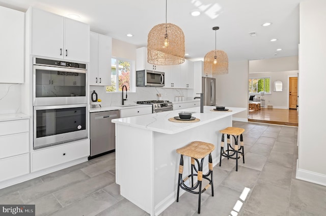 kitchen featuring a center island, appliances with stainless steel finishes, hanging light fixtures, and plenty of natural light