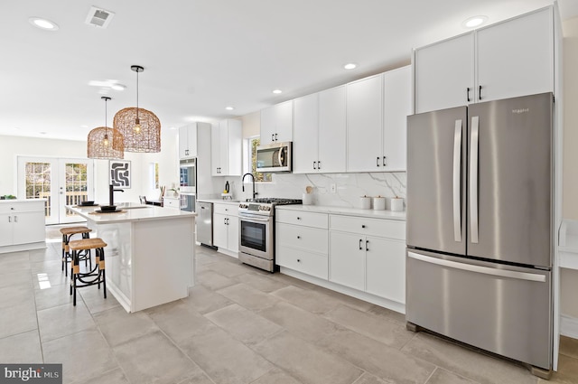 kitchen with pendant lighting, white cabinets, stainless steel appliances, and a center island