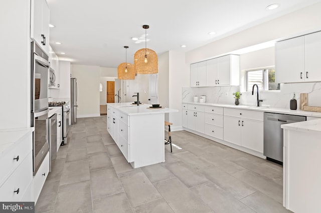 kitchen featuring white cabinets, backsplash, stainless steel appliances, decorative light fixtures, and a center island