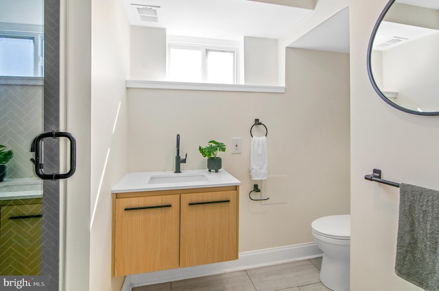 bathroom with vanity, a healthy amount of sunlight, toilet, and tile patterned floors