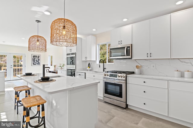 kitchen featuring white cabinets, a kitchen island, sink, decorative light fixtures, and stainless steel appliances